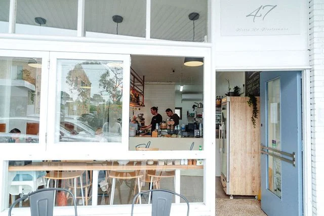 A restaurant with tables and chairs in front of a large window.