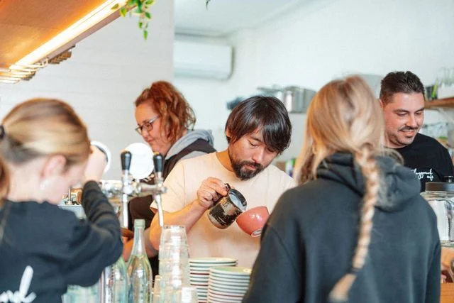 A man is pouring coffee into a cup in a restaurant.