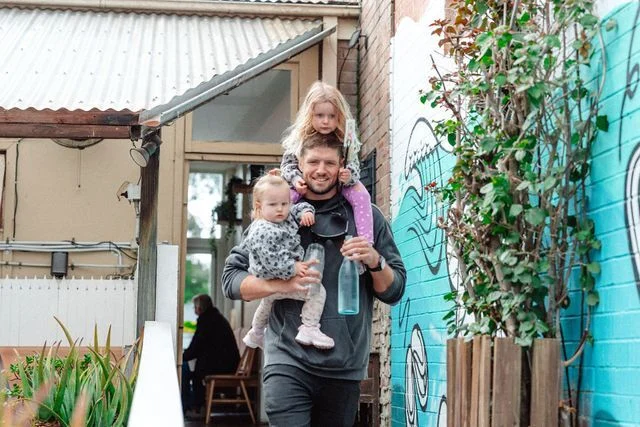 A man is carrying two children on his shoulders.