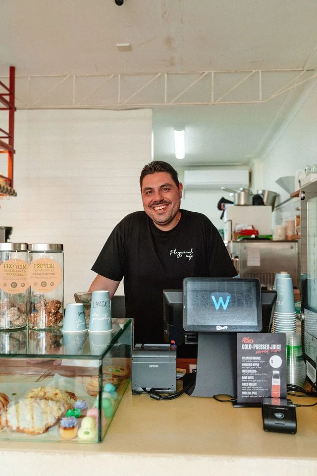 A man is standing behind a counter in a restaurant.