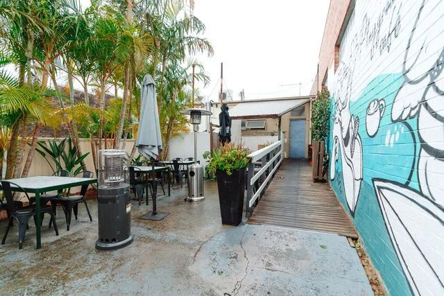 A patio with tables and chairs and a mural on the wall.