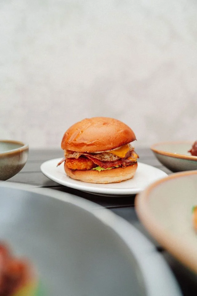 A hamburger is sitting on a white plate on a table.