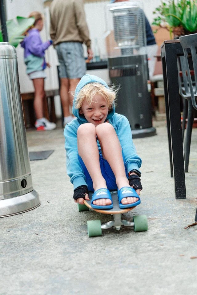 A young boy is riding a skateboard on a patio.