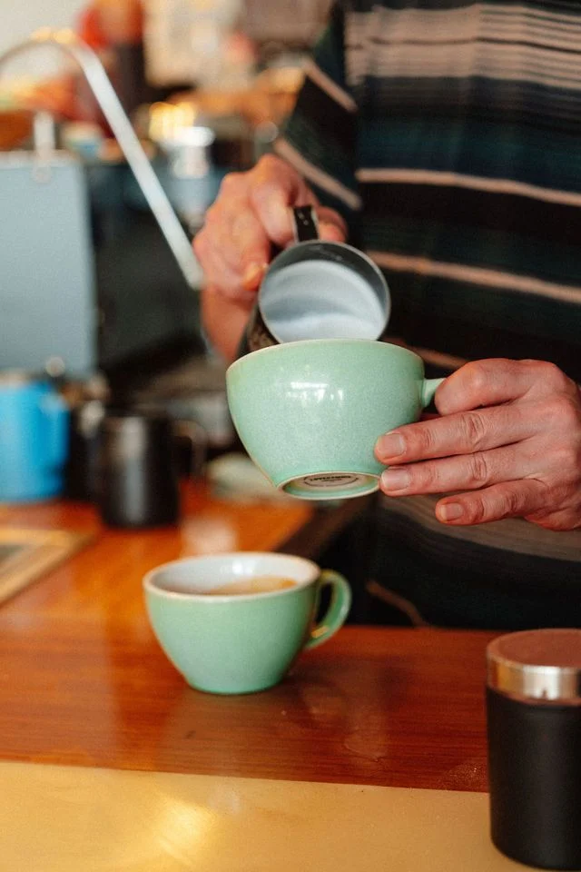Milk being poured into coffee at the counter