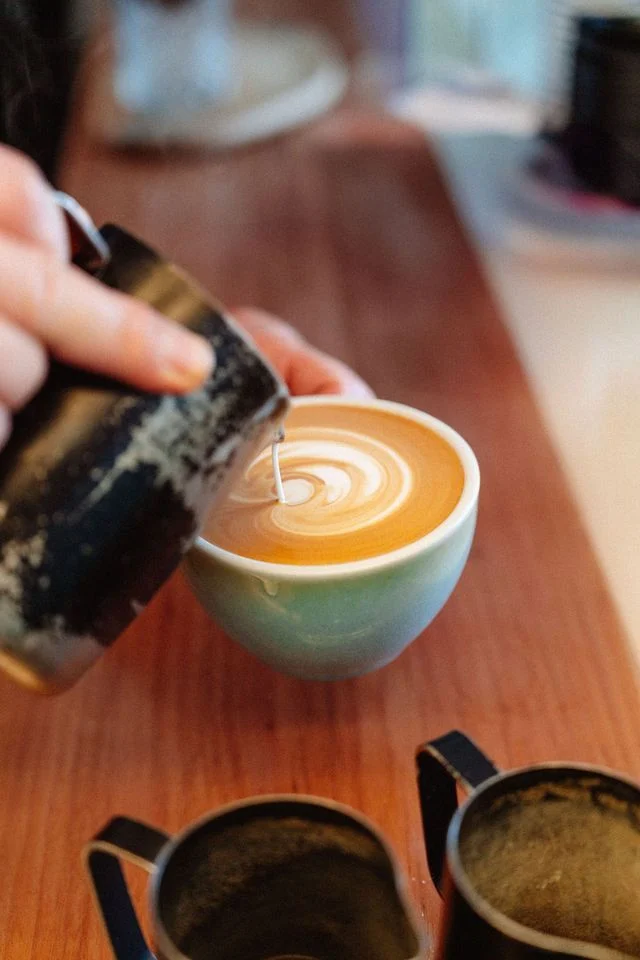 Milk being poured into a teal coffee cup