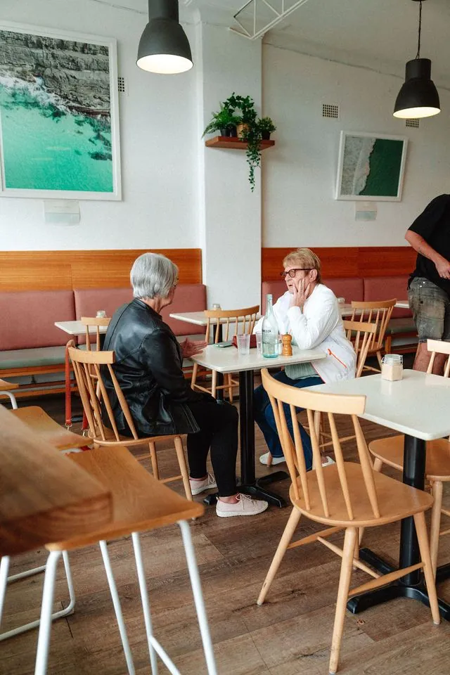 Two friends sharing a table and conversation at Playground Cafe