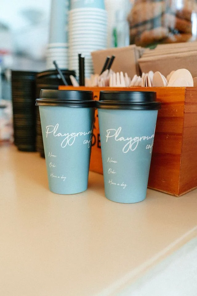 Two teal takeaway coffee cups on the counter